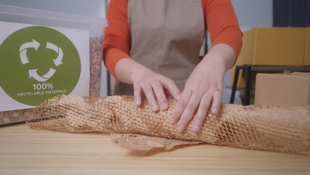 A woman wraps a product with eco-friendly honeycomb paper with label stating "100% Recyclable Materials" highlighting the sustainable practices of a small business