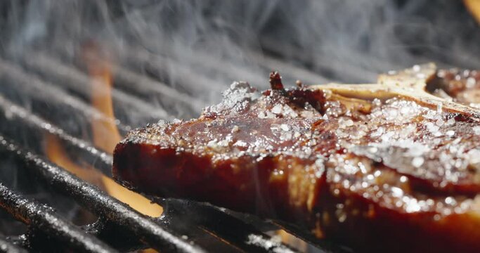 Close-up. Juicy T-bone steak seared to perfection on hot grill, sits on grill, sizzle of meat and aroma of barbecue fill air quintessential summer delight that meat lovers crave, template for title. 