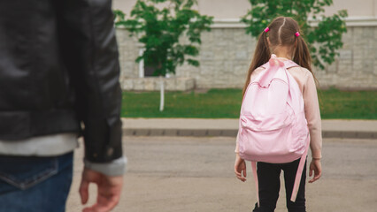 Father with cute little daughter see off to school elementary class outdoor near school building. Child pupil with backpack going dad with love before going classroom