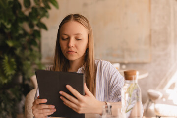 Young smart busy professional business woman executive, female company worker or manager holding digital tablet using pad technology device working sitting in cafe.