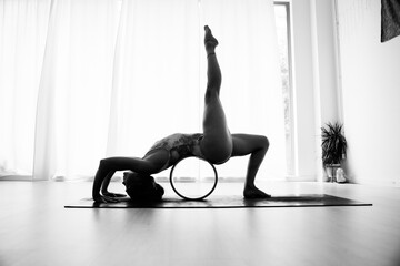 A woman exercise with the help of the yoga wheel