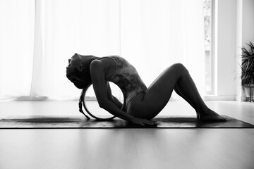 A woman stretches her back and neck with the yoga wheel