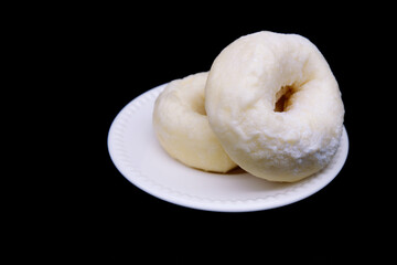 Donut placed on white plate with black background. Close-up donut texture with icing sugar. Snack...