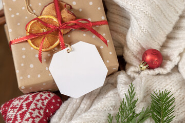 Gift tag on a Christmas present near cosy heart and sweater, mockup