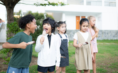 Schoolchildren participating in outdoor activities and relaxing with eating ice cream.