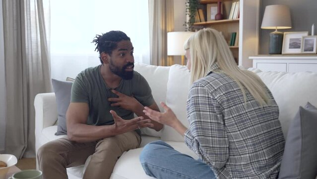Communication problems, relationship difficulties. Young couple man and woman sitting on sofa at home, argue and misunderstanding. Two angry and sad people having issue with ego and guilt.