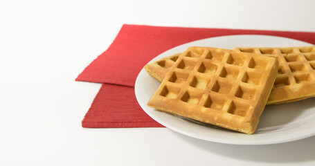 Waffles - Corrugations on a white table decorated with red napkins. Isolated, space for text
