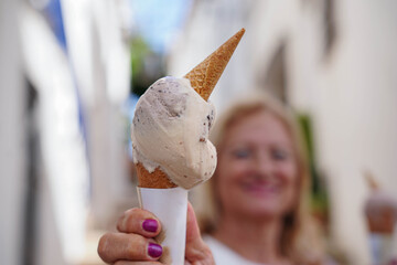 close up of an ice cream and a woman smiling in the background. Sweets in summer