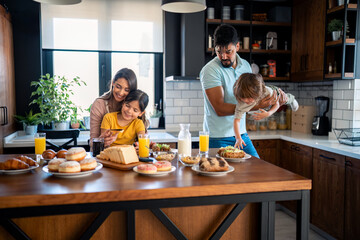 Family meal at home. Young parents with small children having fun during breakfast.