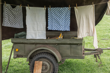 tea towels and a shirt hang outside to dry on a rope line in front of a military tent