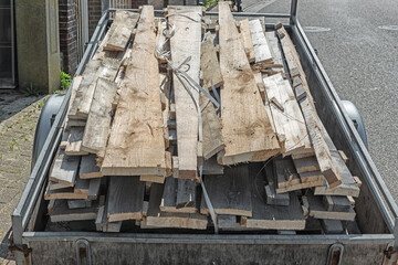 car trailer full of wooden planks is parked outside on the street