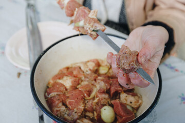 woman hands and marinated pork shashlik on skewers