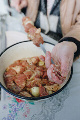 woman hands and marinated pork shashlik on skewers
