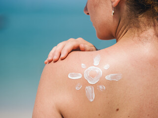 Close-up of a woman's back with sunscreen applied in a sun pattern, highlighting skin protection...