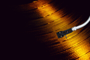 Turntable arm on golden Vinyl record rotating in a macro shot