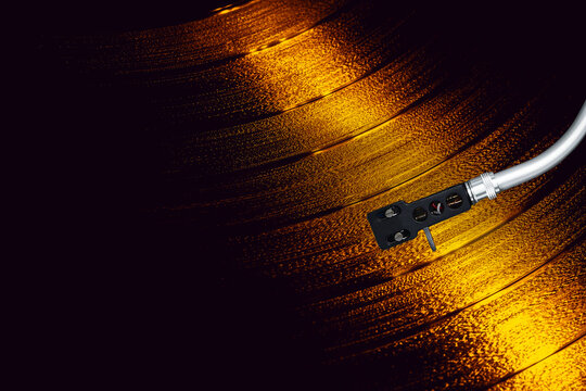 Turntable arm on golden Vinyl record rotating in a macro shot