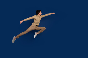 Fototapeta na wymiar Full body photo of attractive young man jump fly superman dressed stylish beige clothes isolated on dark blue color background