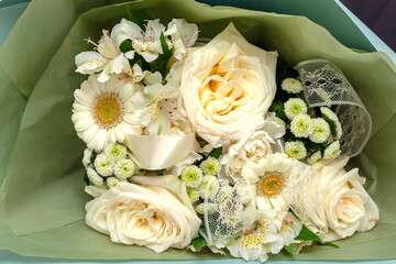 Light pink and peach flowers in vase with greenery.