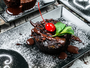 Piece of chocolate brownie cake with chocolate cream and cherries in plate on rustic background....