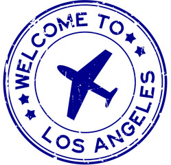 Grunge blue welcome to los angeles word with plane icon round rubber seal stamp on white background