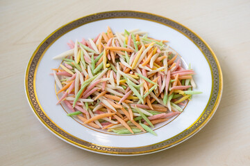 Uncooked Semai pitha or Chui pitha on a white plate on a wooden background. It is a traditional Bangladeshi sweet dish often prepared during festive occasions and family gatherings.