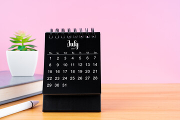 July Mini desk calendar for 2024 year on worktable with pink background.