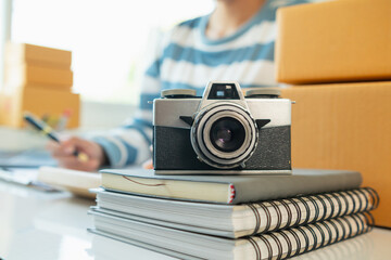 A vintage film camera sits on a table in an office and a book stands out in the background. A...