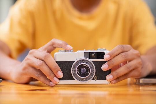 young photographer holds vintage style film camera in her hand and inspects film camera for use after film cameras have become popular with photographers today because of their unique image tones.