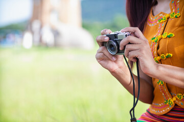 young photographer holds vintage style film camera in her hand and inspects film camera for use...