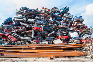 A large heap of rusty scrap cars in a junk yard ready to be recycled
