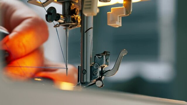 close-up in a sewing workshop thread is inserted into a needle on a machine