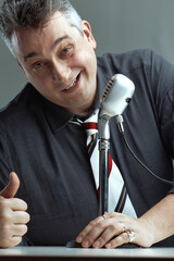 Naklejka premium Man giving thumbs-up, speaking into microphone