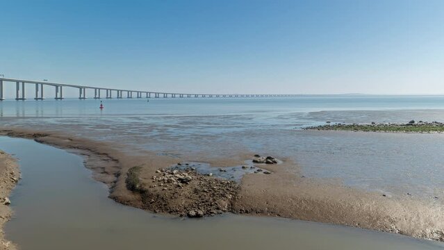 Panorama showing motion from the low to high tide next to Vasco da Gama Bridge in Parque das Nacoes timelapse in Lisbon, Portugal. Level of water is rising up. Waterfront in Park of Nations district