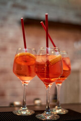Alcoholic cocktail of orange color with red tubes. Work as a bartender in a nightclub