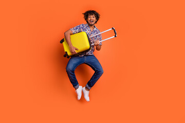Full body photo of attractive young man hold baggage jump dressed stylish colorful clothes isolated...