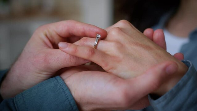 Unrecognizable boyfriend male guy man put luxury ring jewelry on female hand finger at home love marriage romantic woman girl husband wife bridal bride celebration ceremony couple engagement at home
