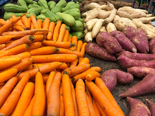 Carrots, sweet potatoes, and chayotes in bulk in the produce section of the supermarket.