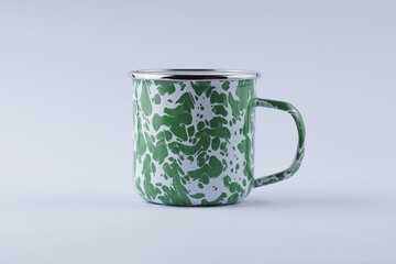A typical Indonesian green and white iron cup on a white table with studio lighting