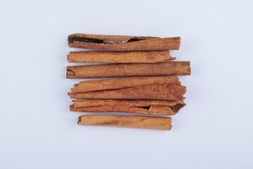 several pieces of cinnamon bark spice on a white table with studio lighting