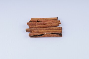 several pieces of cinnamon bark spice on a white table with studio lighting