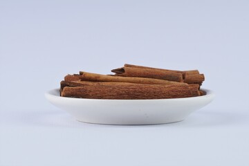 several pieces of cinnamon bark spice on a white table with studio lighting