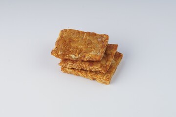 pieces of fried tempeh on a white plate on a white table with studio lighting