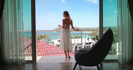 Tourist female have morning coffee on balcony terrace exotic resort hotel enjoy ocean view. Elegant...