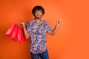 Photo portrait of attractive young man shopping bags point empty space dressed stylish colorful...