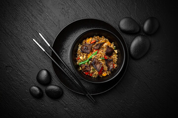 Wok rice with beef. Сomposition on black background. The Art of Japanese Cuisine. Food photography for menu and sushi bar decoration