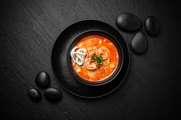 Composition of tom yam soup with shrimp and noodles on black background. The Art of Japanese Cuisine. Food photography for menu and sushi bar decoration 