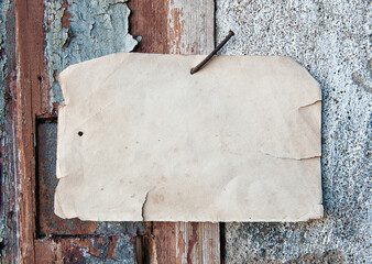 Old paper advertisement hanging on aged wall nailed by rusty doornail