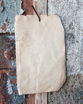Old paper advertisement hanging on aged wall nailed by rusty doornail