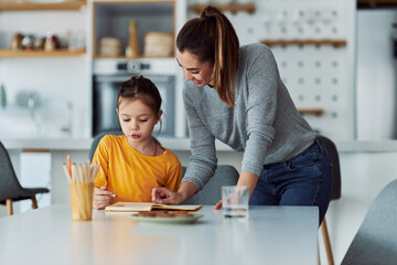 A caring mother helping her young daughter with her homework