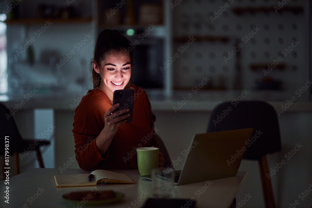 Wall mural a happy young adult woman scrolling through her phone late at night and relaxing